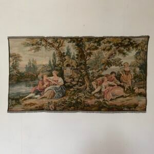Magnifico arazzo in stile rococò raffigura una scena bucolica incantevole, intrisa di eleganza e serenità. Un gruppo di dame e cavalieri si rilassa in un paesaggio lussureggiante